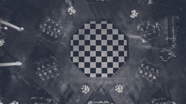 Overhead view of a chequered dance floor surrounded by round dinner tables, in a dark blue tone.